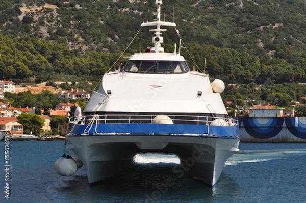 Fototapeta Cres, Croatia, July 28, 2024. The catamaran sailing into the city harbor. The catamaran with passengers sailing into the city harbor. Jadrolinija catamaran.