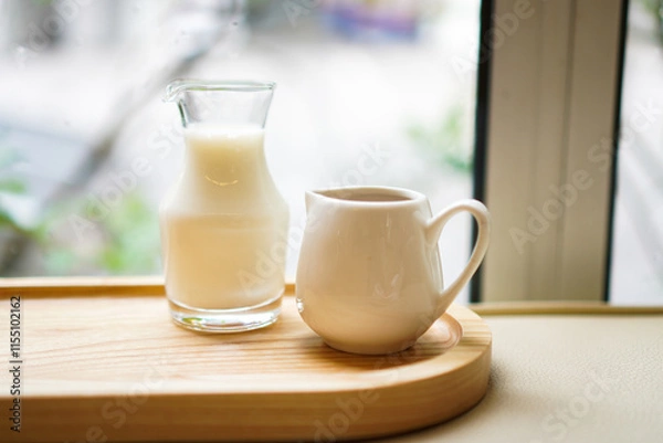 Fototapeta A glass jar of milk and a cup of espresso on a wooden tray with selective focused.