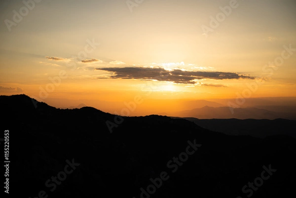 Fototapeta Atardecer entre las montañas con tonos naranjas