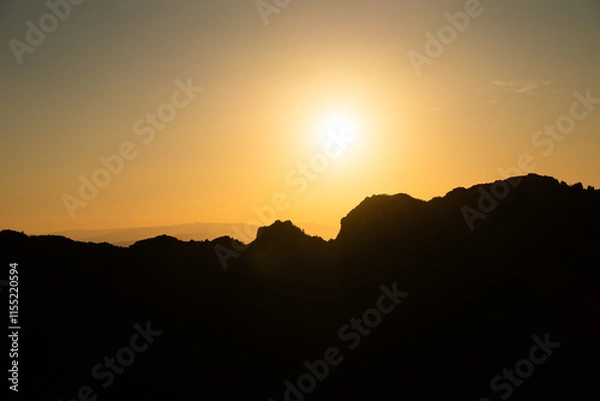 Fototapeta Atardecer entre las montañas con tonos naranjas