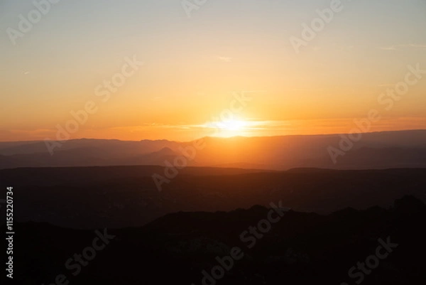 Fototapeta Atardecer entre las montañas con tonos naranjas