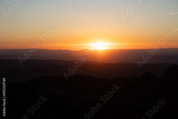 Fototapeta Atardecer entre las montañas con tonos naranjas