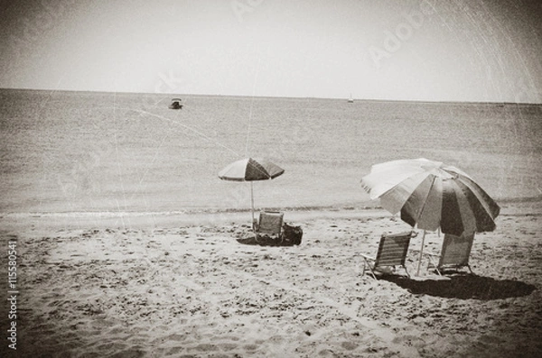 Fototapeta Beach umbrellas and chairs on a beach in Eastham, MA Cape Cod, vintage look.