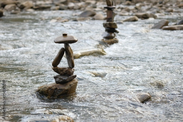 Fototapeta Two figures made of river stones in the middle of the stream.