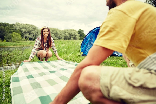 Fototapeta happy couple laying picnic blanket at campsite