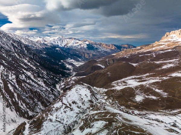 Fototapeta Beautiful aerial view of snowy peaks in a picturesque gorge. Landscape and nature of the North Caucasus