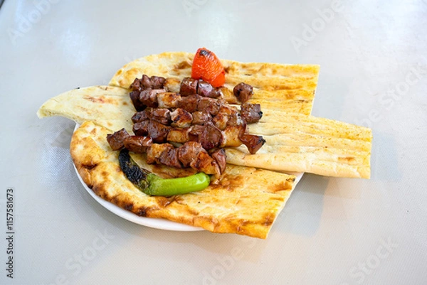 Fototapeta Famous Urfa meat liver, ciger wrapped by lavash with roasted chili pepper, onion and sauce in Sanliurfa, Turkey. Kuzu et ciger sis. Izgara dana bonfile, cop sis, kuzu pirzola. Karisik kebap, beyti keb