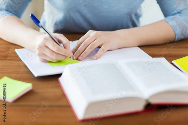 Fototapeta close up of student with book and notebook at home