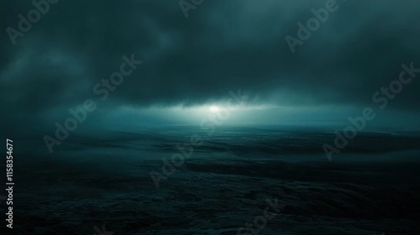 Fototapeta A moody seascape under dark clouds with a faint light breaking through.