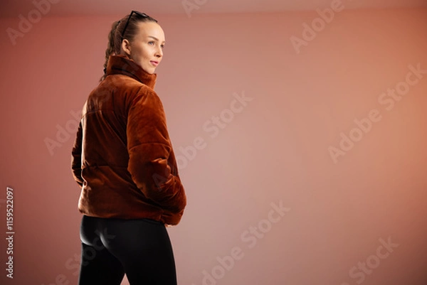 Obraz Young woman wearing brown coat posing in modern and clean studio setting