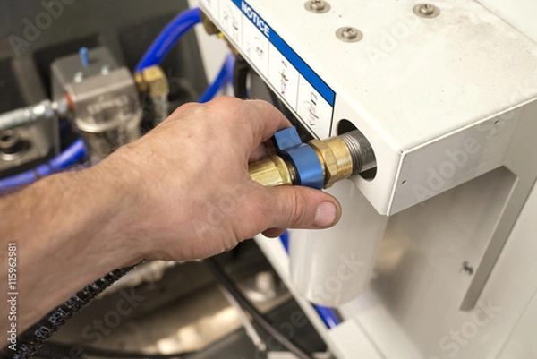 Fototapeta Hand of a man is tightening union nut of the hydraulic pipe