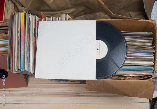 Fototapeta Retro styled image of a collection of old vinyl record lp's with sleeves on a wooden background. Top view.  Copy space
