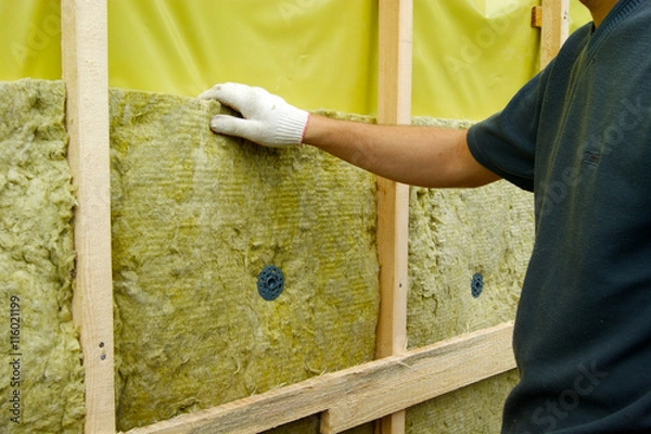 Fototapeta The man is engaged in construction work on the exterior isulation of the house with mineral wool
