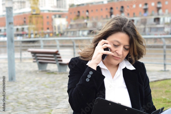 Fototapeta Portrait of business woman talking on her smartphone and reading