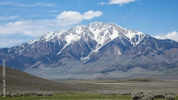 Fototapeta Majestic Mountain Peak: A majestic snow-capped mountain peak rises against a clear blue sky, its rugged slopes reaching for the heavens.
