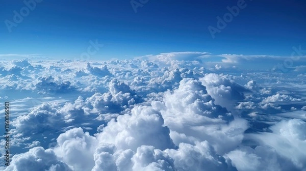 Fototapeta Aerial view of fluffy white clouds against a vibrant blue sky.