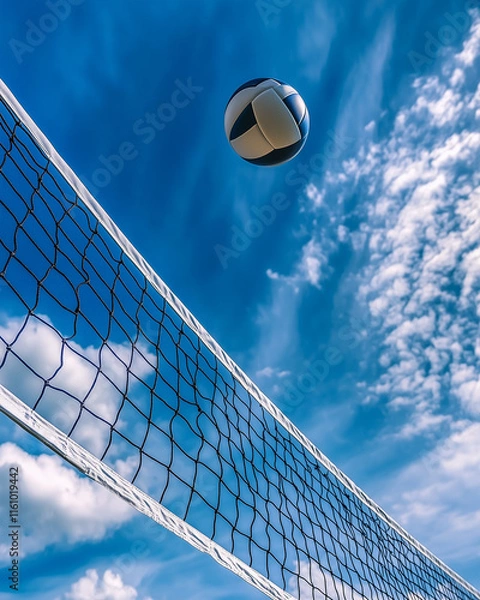 Fototapeta Dramatic shot of a volleyball net with a ball caught mid-air above it, under a vibrant blue sky