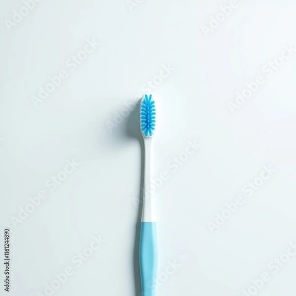 Fototapeta A single toothbrush with light blue bristles and handle stands upright against a white background.