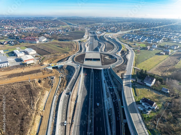 Fototapeta Krakow, Poland.  Zielonki highway junction with traffic circle on S52 highway, part of motorway ring road around Cracow, opened for traffic on December 23, 2024. Viaducts, tunnels, ramps. Aerial view