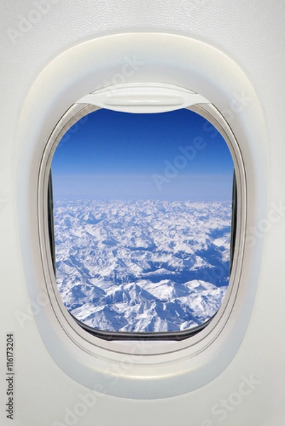 Fototapeta Window of an airplane from inside, view on snowy mountains (the Alps)