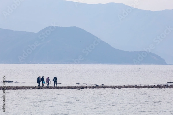 Fototapeta 2024 Dec 26,Hong Kong ,People are seen strolling along the tombolo on Sharp Island, The tombolo is not always visible as it emerges only when low tide.