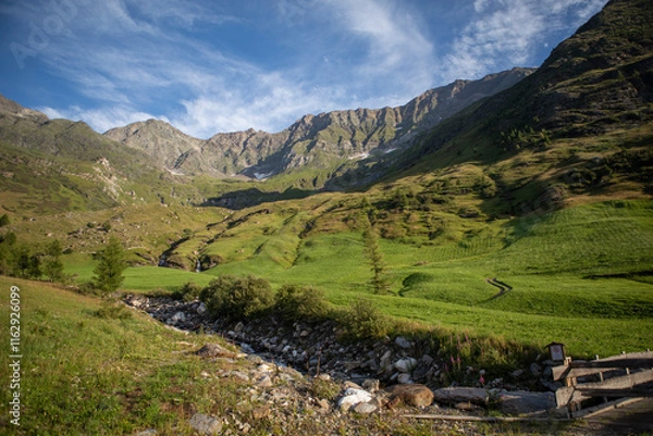 Obraz Scenic mountain landscape in Tyrol, Austria. Rolling green hills, rugged alpine peaks, and a clear blue sky capture the peaceful beauty of the summer Alps.