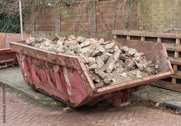 Obraz red-colored open steel industrial waste container filled with stone waste