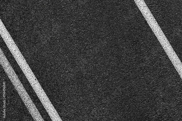 Fototapeta Level asphalted road with a dividing white stripes. The texture of the tarmac, top view.