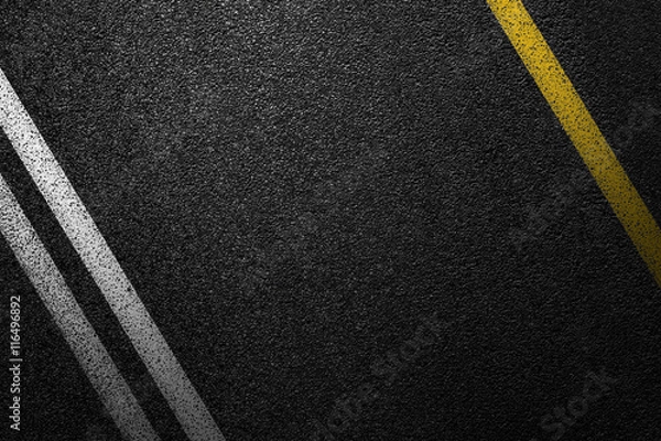 Fototapeta Level asphalted road with a dividing white and yellow stripes. The texture of the tarmac, top view.
