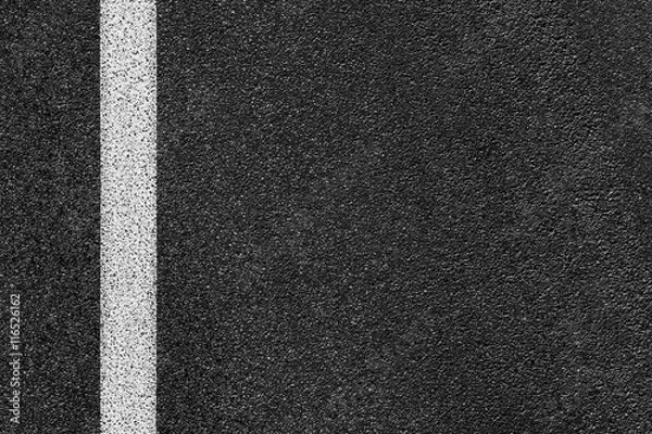 Fototapeta Level asphalted road with a dividing white stripes. The texture of the tarmac, top view.