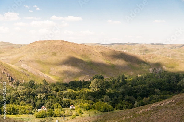 Fototapeta The shadow of clouds on the wooded rolling hills.