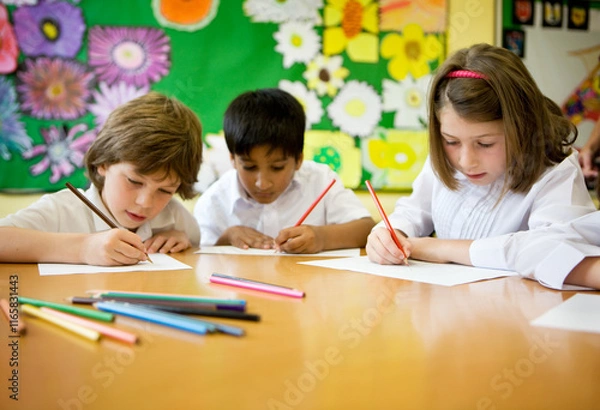 Fototapeta Elementary School: Artists. A small group of young primary school children in the classroom developing their creative drawing and art skills.