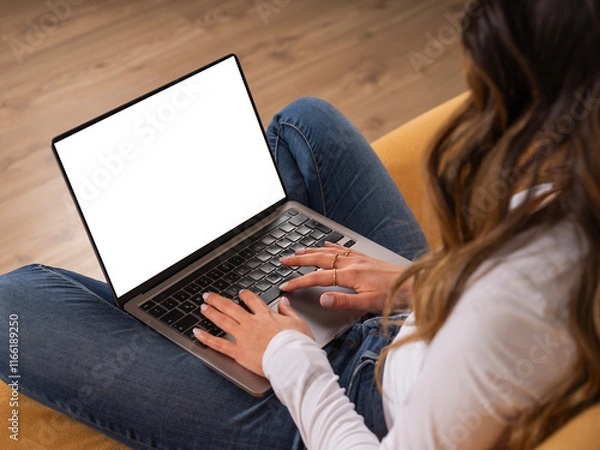 Fototapeta Over shoulder laptop mock up, young caucasian brunette teen girl student sitting couch at home relaxing using holding laptop with empty blank screen. Online learning, watching movie, shopping online.