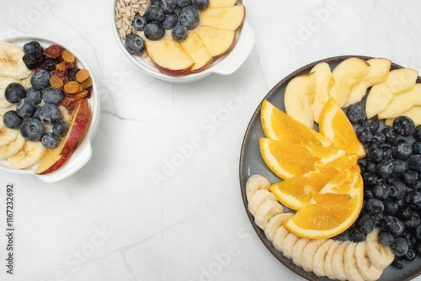 Fototapeta Top view of a breakfast spread featuring fresh fruits, glass of juice, blueberries, orange slices, apple slices, banana, and sunflower seeds, arranged neatly on plates. mindful eating and a balanced d