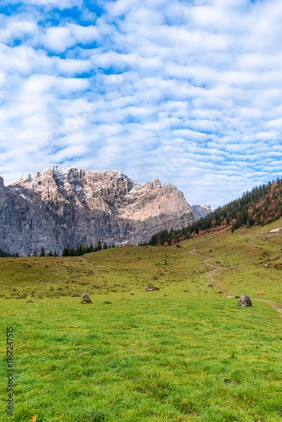 Fototapeta Colorful autumn landscape at Großer Ahornboden in the Karwendel Mountains, Austria – forest with fall foliage, rocky peaks and dramatic sky