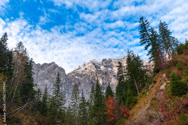 Fototapeta Colorful autumn landscape at Großer Ahornboden in the Karwendel Mountains, Austria – forest with fall foliage, rocky peaks and dramatic sky