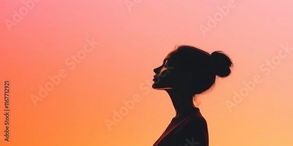 Obraz A woman is standing in front of a pink sky. She is wearing a red shirt and has her hair in a bun. Concept of calmness and serenity, as the woman is lost in thought