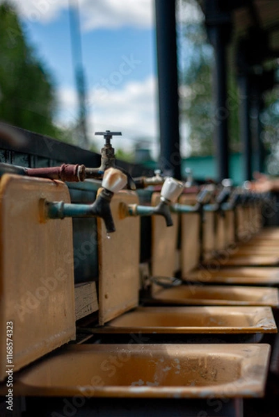 Obraz Water taps in the washbasins of a children's summer camp. Old faucets in washstands. Cranes in public washbasin for hygiene in the street.