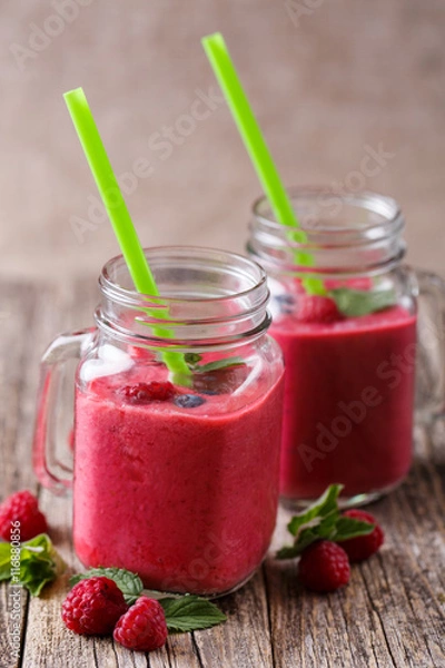 Fototapeta Tasty raspberry smoothie in glass jar on wooden table.