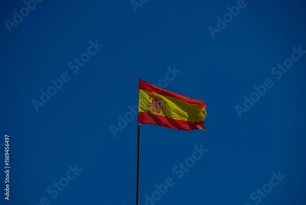 Fototapeta The Spanish national flag flies on a flagpole 