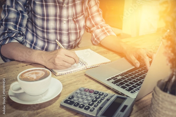 Obraz close up hand of business man using laptop computer and write on