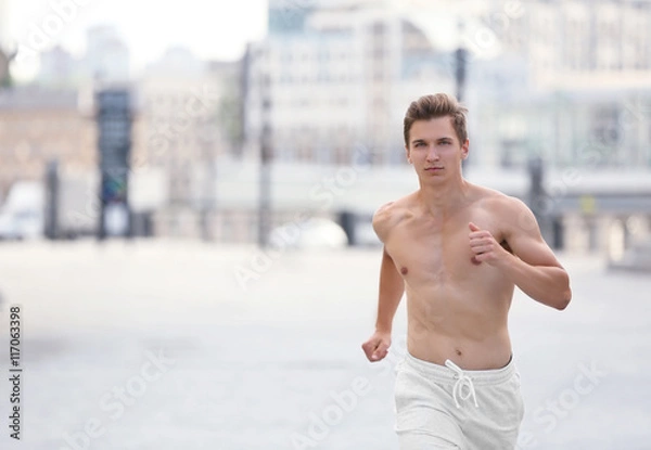 Fototapeta Young man running on the street