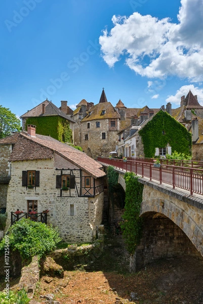 Fototapeta Titel: View at the medieval village of Carennac in Lot Occitanie Southern France with bridge under a blue sky with clouds in summer