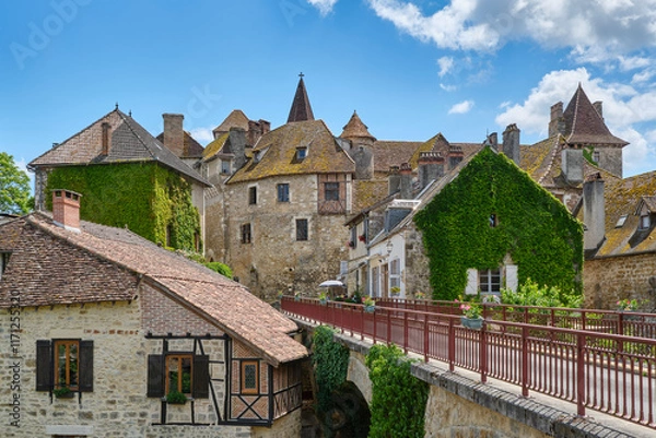 Fototapeta Titel: View at the medieval village of Carennac in Lot Occitanie Southern France with bridge under a blue sky with clouds in summer