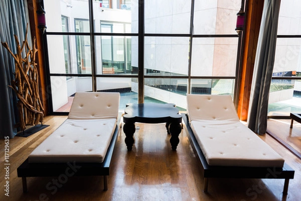 Fototapeta Loungers for massage or relaxation with small table and big window in Spa