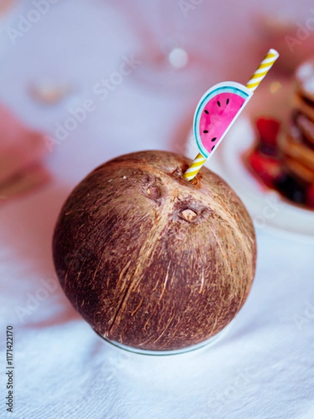 Obraz Coconut with a straw on a festive table close-up