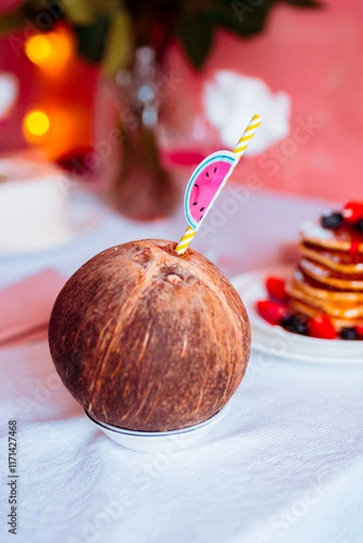 Obraz Coconut with a straw on a festive table close-up