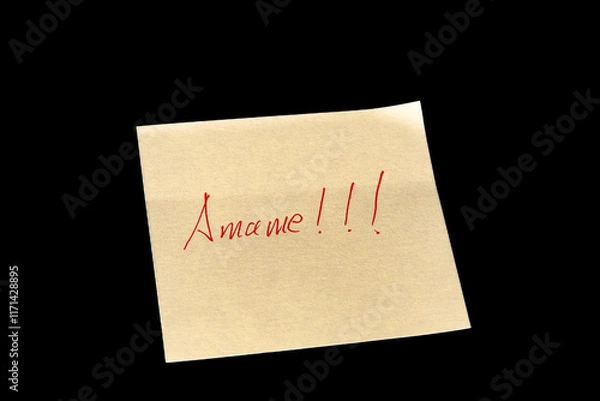 Fototapeta Yellow adhesive paper, similar to a Post-it note, on a black background with the words “Amame” “Love me” in Spanish handwritten in red ink.