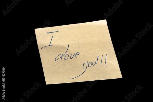 Fototapeta Yellow adhesive paper, similar to a Post-it note, on a black background with the words “I Love You” handwritten in blue ink.