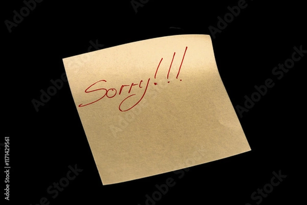 Fototapeta Yellow adhesive paper, similar to a Post-it note, on a black background with the words “Sorry” and three exclamation marks handwritten in red ink.